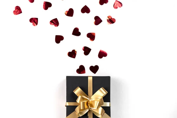 Fondo del Día de San Valentín. Caja de regalo hecha a mano decorada con confeti corazón rojo sobre fondo blanco. Estilo mínimo y concepto de día de San Valentín. Plano, vista superior, espacio para copiar — Foto de Stock