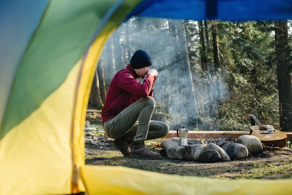 Bild von einem Blick vom Zelteingang des jungen Mannes Reisenden trinkt Kaffee mit Blick auf erstaunliche Wald, schöne und inspirierende Lage des Lagers. Reisen echte Wildnis Lebensstil erkunden — Stockfoto