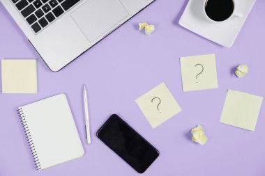 Yapışkan notlardaki soru işareti, not defteri, dizüstü bilgisayar, fincan kahve, telefon, menekşe arkaplamalı kalem. Faq konsepti. Müşterilerle çalışmak. İşte sorunlar var. Düz konum, üst görünüm, kopyalama alanı