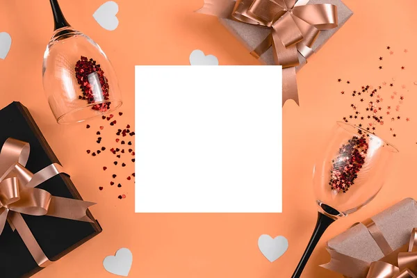 Fondo de vacaciones. Dos copas de vino tintineo, varias cajas de regalo hechas a mano decoradas con confeti de corazón rosa, marco blanco sobre fondo naranja. Concepto de San Valentín. Plano, vista superior, espacio para copiar — Foto de Stock