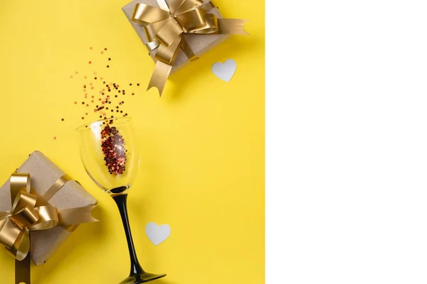 Valentijnsdag achtergrond. Clinking wijnglazen, diverse handgemaakte geschenkdozen versierd met roze hart confetti op gele achtergrond. Valentijnsdag concept. Vlakke lay, bovenaanzicht, kopieerruimte — Stockfoto