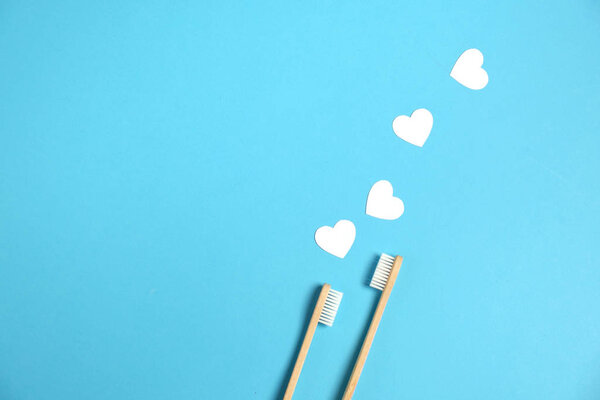 Zero waste concept. Two wooden bamboo eco friendly toothbrushes, white hearts on blue background. Eco friendly, valentines day concept. Flat lay, copy space