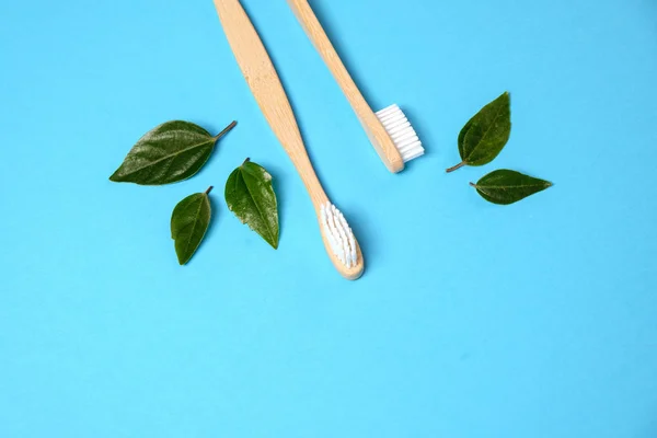 Zero waste. Two wooden bamboo eco friendly toothbrushes and green leaf on blue background. Dental care and Eco friendly and reuse concept. Flat lay, top view, copy space — Stock Photo, Image