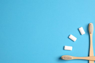 Diş bakımı. İki ahşap bambu çevre dostu diş fırçası ve mavi arka planda saatler şeklinde sakız. Çevre dostu ve konsepti yeniden kullan. Düz konum, üst görünüm, kopyalama alanı