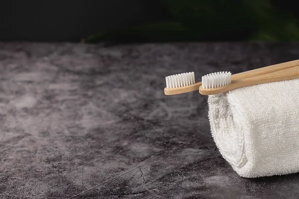 Duas escovas de dentes de bambu naturais eco e toalha branca sobre fundo cinza. Estilo de vida sustentável e zero desperdício de casa. Cuidados dentários e Eco amigável e conceito de reutilização. Espaço de cópia — Fotografia de Stock