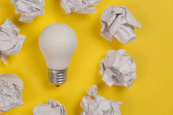 Inspiration de créativité, concept d'idée d'entreprise avec ampoule blanche et boule froissée en papier sur fond jaune. Pose plate, vue du dessus, espace de copie — Photo