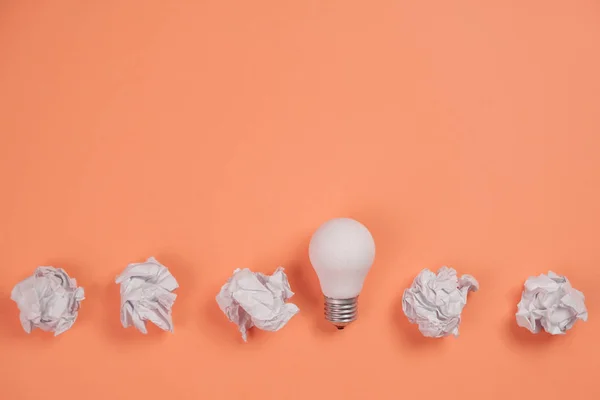 Inspiration de créativité, concept d'idée d'entreprise avec ampoule blanche et boule froissée en papier sur fond orange. Pose plate, vue du dessus, espace de copie — Photo
