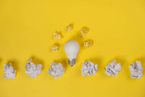 Inspiration de créativité, concept d'idée d'entreprise avec ampoule blanche et boule froissée en papier sur fond jaune. Pose plate, vue du dessus, espace de copie — Photo