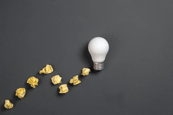 Inspiration de créativité, concept d'idée d'entreprise avec ampoule blanche et boule froissée en papier sur fond gris. Pose plate, vue du dessus, espace de copie — Photo