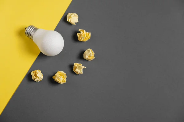Inspiration de créativité, concept d'idée d'entreprise avec ampoule blanche et boule froissée en papier sur fond gris et jaune. Pose plate, vue du dessus, espace de copie — Photo