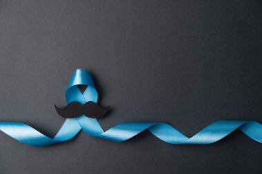 Symbol for support men. Top view on blue Ribbon with mustache for supporting people living and illness. Healthcare, International men, Father and World cancer day concept. Flat lay, copy space clipart