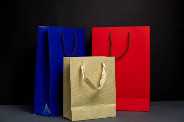 Siyah arkaplanda izole edilmiş üç renk alışveriş torbası var. Paketleme şablonu modeli. Teslimat konsepti reklam taklidi. Alışveriş Konsepti