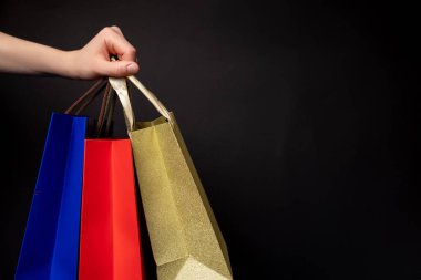 Siyah izole edilmiş arka planda renkli alışveriş çantalarını tutan kadın elini kapat. Alışveriş ve teslimat konsepti reklam taklidi. Boşluğu kopyala
