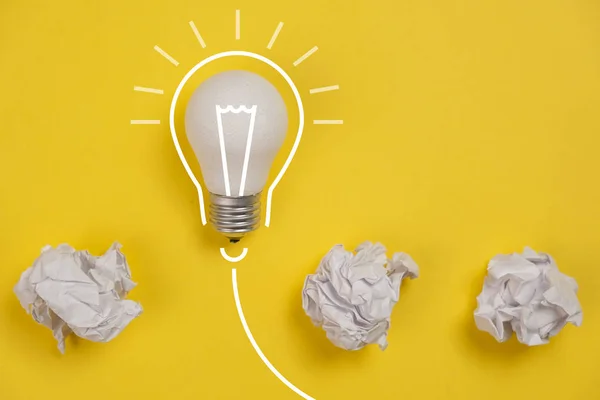 Neues Ideenkonzept mit zerknittertem Büropapier und weißer Glühbirne auf gelbem Hintergrund. kreative Lösung während des Brainstormingkonzepts. flache Lage, Draufsicht, Kopierraum — Stockfoto