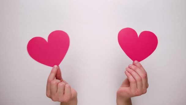 女性的手通过白纸墙握住红纸心脏 情人节和喜欢写博客的社交网络温情的概念 — 图库视频影像