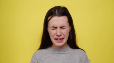 Stressed anxious young woman tearing hair out feeling tension and stress while facing problems, can't stand pressure, clenching teeth, isolated over yellow background. Negative human emotions concept