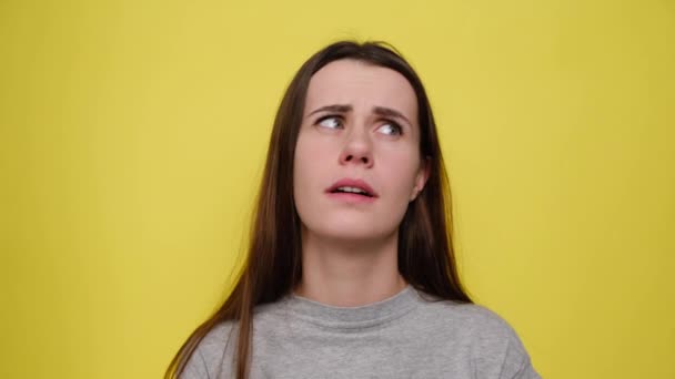 不幸な落ち込んで若い女性が彼女の寺院では 灰色のTシャツを着て 黄色の背景に隔離された指銃のジェスチャーを示す 否定的な人間の感情や感情の概念 — ストック動画