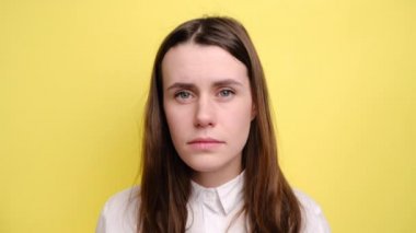 Dilini dışarı çıkaran tiksindirici kız kötü koku yüzünden midesi bulanıyor, hoşnutsuzluk içinde kaşlarını çatıyor, beyaz gömlek giyiyor, sarı arka planda izole edilmiş. Kötü koku konsepti.