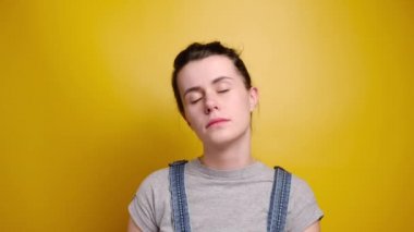 Sağlıklı huzurlu uyku konsepti. Çekici, sakin, mutlu yüzlü, uyuyormuş gibi yapan, gözleri kapalı, sarı stüdyo arka planında uyuyormuş gibi yapan genç bir kadın.