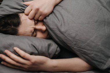 Üzgün, genç bir kadın, yastıkla başını örtmüş yatarken mutsuz ve yalnız hissediyor, aldatıyor, mutsuz bir kız, erkek arkadaşından ayrıldığı için acı çekiyor, istenmeyen hamilelik, psikolojik bir sorun.