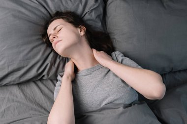 Sabahları yatakta yatan mutsuz genç bir kadın her gece boyun ağrısı, masaj kasları, omuz ağrısı çeken bitkin bir kız. Fibromiyalji kavramı