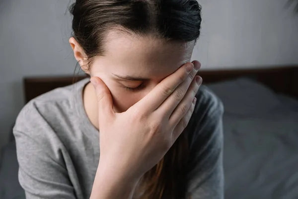 悲伤疲惫的 不健康的年轻女子 闭着眼睛坐在客厅的床上 双手抱头 患有剧烈的突发性头痛或偏头痛 悲伤的概念 — 图库照片