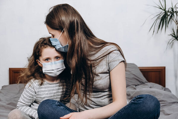 Портрет нездоровой молодой белой семьи в медицинской маске, сидящей дома на кровати, концепции коронавируса или COVID-19 симптомы пандемических заболеваний, гриппа и вирусных инфекций, здравоохранения
