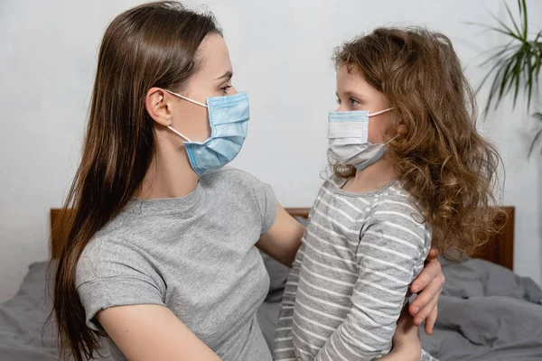 Niña Infeliz Sentada Cama Con Madre Preocupante Con Máscara Virus —  Fotos de Stock