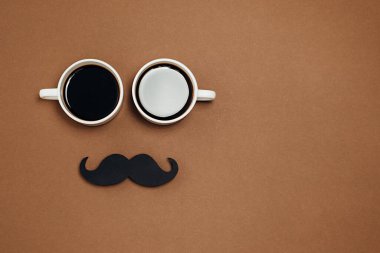 Erkekler sağlık farkındalığı ayı babalar günü erkeklik kavramı. İki fincan kahveyle düz kompozisyon ve eski tarz siyah fotoğraf kabini kahverengi arka planda bıyıkları destekliyor, metin için yer var..