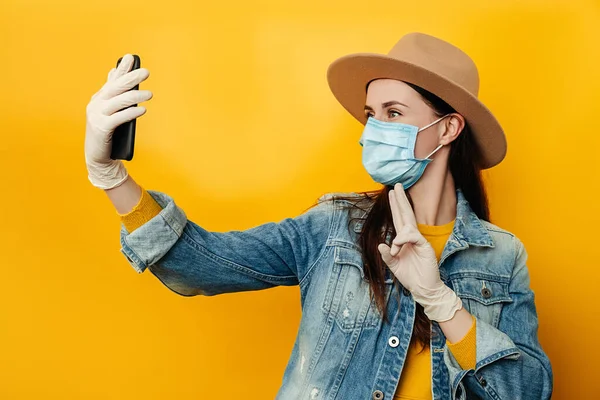 전화를 브루넷 여성은 노란색 배경에 재킷을 코로나 바이러스로부터 자신을 보호하기 — 스톡 사진