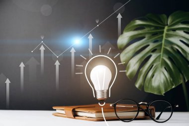 Ev ofisinin çalışma masasında bir defter, yenilikçi teknoloji ve yaratıcılık içeren ampul, kalem, fincan kahve, canavar yaprakları ve gri arka planda gözlük. Boşluk düzenleme şablonunu kopyala