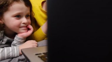 Küçük kıza dizüstü bilgisayarı kullanmayı öğretirken, çizgi film izlerken ya da bilgisayar başında video görüşmeleri yaparken, anne kız dizüstü bilgisayara bakar ve evde çadırda vakit geçirir.