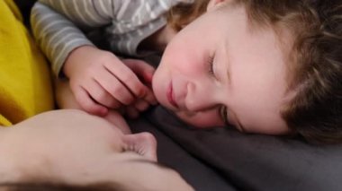 Şakacı, gülen bir anne ve küçük tatlı bir kızın yatakta yüz yüze yatıp yatak odasında boş vakit geçirmesinin yan görüntüsü. Aile eğlencesi kavramı.