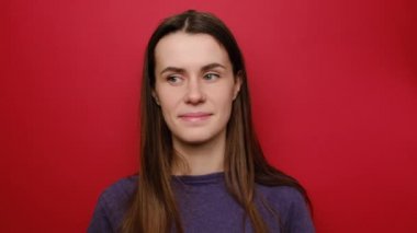 Kadın portresi sır verir ve sorar sessiz ol, işaret parmağını dudaklara bastır, sözler sessiz kal, ifadeleri etkiledi, sırları ve dedikoduları gizledi, kırmızı arka planda izole edilmiş bir tişört giyer,