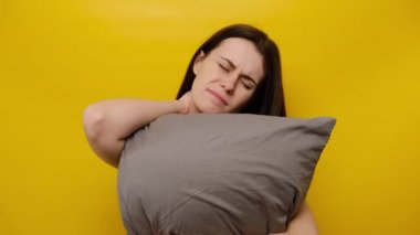 Üzgün kadın yastığı kucaklıyor, her gece boynundaki ağrıyı hissediyor, uyandığında aniden ağrısı ya da kasılması, uykusunda yanlış duruş, sarı arka planda izole edilmiş. Fibromiyalji kavramı