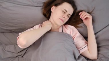 Yorgun, genç bir kadının masaj sonrası gergin boyun kaslarının yatakta yatışı, stres atımı, acı çeken bitkin kız, fizik rahatsızlığı. Fibromiyalji kavramı