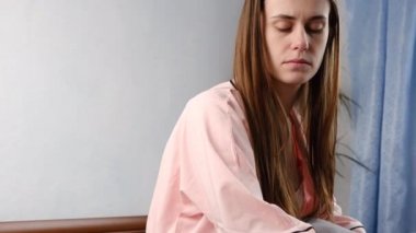 Pijamalı, çaresiz bir kadın yatağa uzanıp başka tarafa bakıyor. Endişeli, stresli genç bir kız. Psikolojik sorunları düşünüp hata yapmaktan pişmanlık duyuyor.