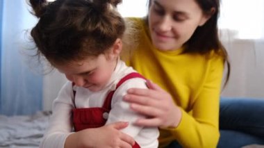 Sevgi dolu anne, üzgün küçük kızının yanında oturup özür diliyor. Genç bir anne, üzgün bir anaokulu kızını, kavga üstüne kavga, ebeveyn ve çocuk empatisi ve şefkat ile teselli ediyor. Aile sorunları kavramı.