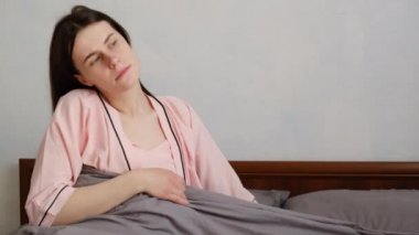 Uykudan sonra yorgun ve üzgün bir kız evde yatarken kalp ağrısı çekiyor. Genç bir kadın göğsüne dokunarak kalp krizi geçiriyor. Enfarktüs veya kadın kalp hastalığı konsepti