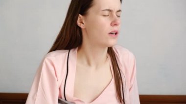 Genç bir kadının göğüs ağrısı kalp krizi geçirmesi, yorgun üzgün bir kızın kalp ağrısı, evde oturması, damar tıkanıklığı ya da kadın kalp hastalığı konsepti.