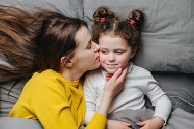Neşeli annenin yanaktan öptüğü sevimli, sevimli kızın yatakta yattığı, gülümseyen anne ya da dadı dinlenmesi, küçük kızın anneyle olan şefkatli anının tadını çıkarması, aşk. Akrabaların aile kavramı