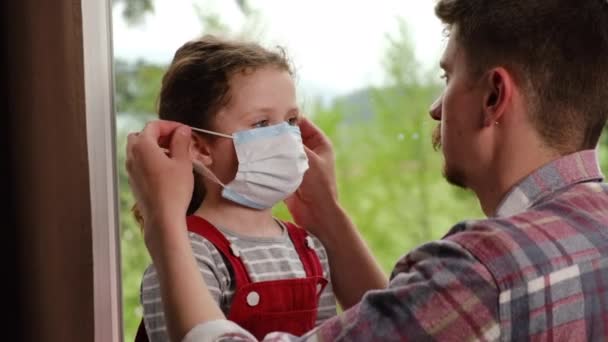 Zorgvuldige Vader Helpt Haar Dochter Gekleed Virus Masker Zittend Vensterbank — Stockvideo
