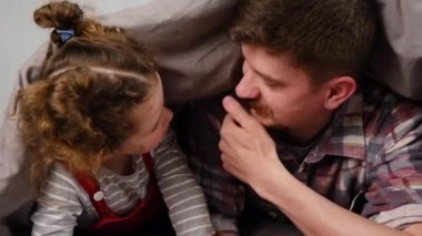 Mutlu, genç bir babanın, tatlı kızıyla yatakta battaniyeyle yatarken konuştuğu anı. Sakallı baba ve küçük kız, sıcak bir evde ebeveyn ve çocuğun birbirine bağlandığı tatlı anların tadını çıkarıyorlar.