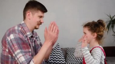 Mutlu genç baba ve tatlı kız evde patatesli kek oynuyorlar, kaygısız baba ve küçük kız ailesi el çırpıyorlar birlikte eğleniyorlar evde oturup eğlenceli oyunlar oynuyorlar.