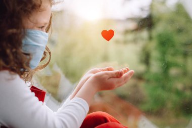 Şirin küçük kız, Coronavirus COVID-19 salgını sırasında hastanede çalışan doktorlara ve sağlık çalışanlarına teşekkür etmek için küçük kalbinin yanında oturan maske takıyor.