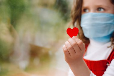 Hemşire günü konsepti. Küçük kırmızı kalpli kız, Coronavirus COVID-19 salgını sırasında hastanede çalışan doktorlara ve tıbbi personele teşekkür etmek için hemşirelerine bir yol sunuyor. Seçici odak