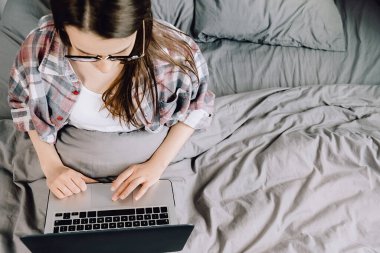 Genç bir kadının evde dizüstü bilgisayar kullanması, esmer bir kızın sosyal ağlarda haberlere bakması, bilgisayarda çalışması, blog yazması veya internet alışverişi yapması. Seçici odak
