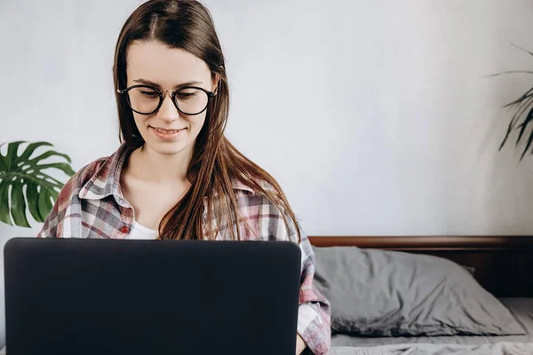 Mulher Atraente Óculos Sentado Cama Trabalhando Com Laptop Pensando Post — Fotografia de Stock
