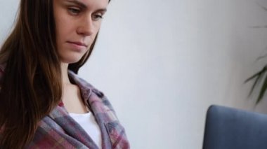 Evdeki battaniyenin altında rahat bir yatakta oturup uzaktan video görüşmesi yapan dizüstü bilgisayar ekranına bakan güzel bir kız. Web kamerasıyla konuşan güzel bir kız. Sosyal uzaklık