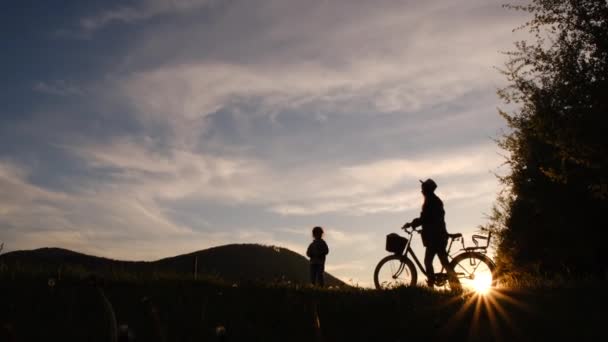 Silhouetten Van Jonge Moeder Met Hoed Dochtertje Wandelend Met Fietsen — Stockvideo